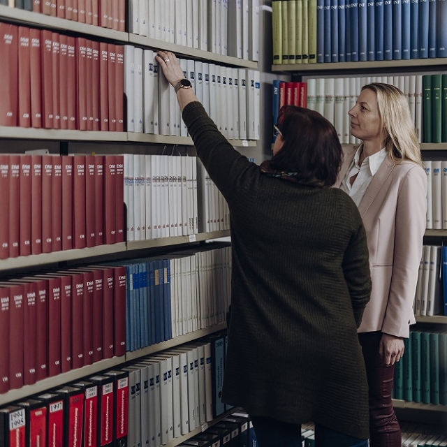 Zwei Kolleginnen auf der Suche nach einem Buch in unserer Bibliothek