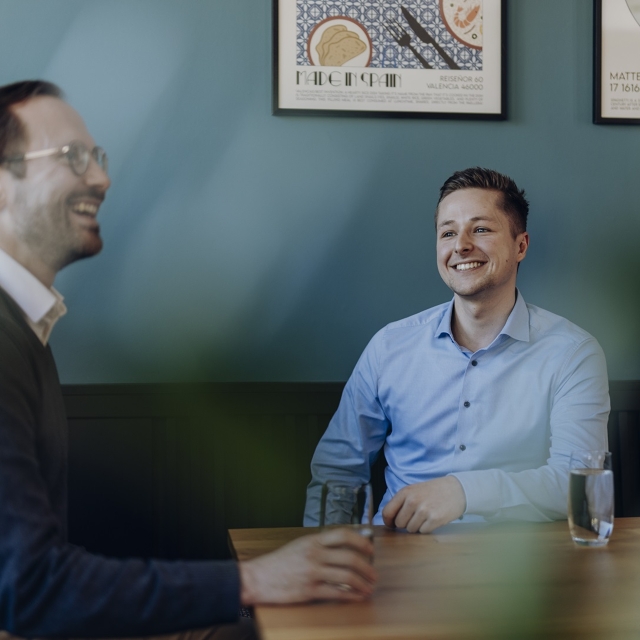 Finanzbuchhalter (m/w/d) Kollegen sitzen am Tisch bei einer Unterhaltung